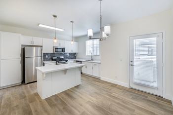 An open kitchen with a large island and a stainless steel refrigerator